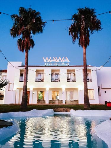 a building with two palm trees and a pool of water at Wawa Tarifa in Tarifa