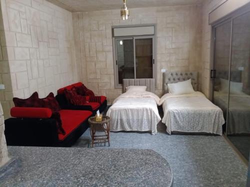 a bedroom with two beds and a red couch at بيت مريم in Irjān