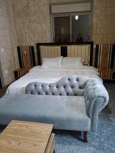 a bedroom with a large bed with a tufted foot board at بيت مريم in Irjān