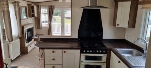 a small kitchen with a stove and a sink at Maisy's Retreat in Chapel Saint Leonards