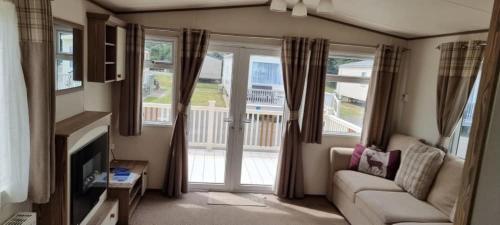 a living room with a couch and a window at Maisy's Retreat in Chapel Saint Leonards