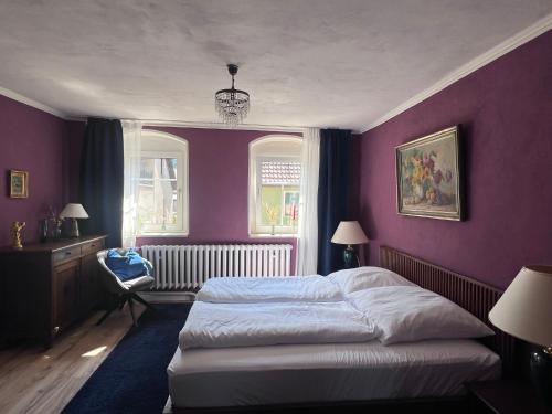 a bedroom with purple walls and a bed and a chair at Casa Vinea in Freyburg