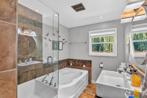 a bathroom with a tub and a shower and a sink at Waterfront Oasis with Pool, Hot Tub & Pet Friendly in Kelowna