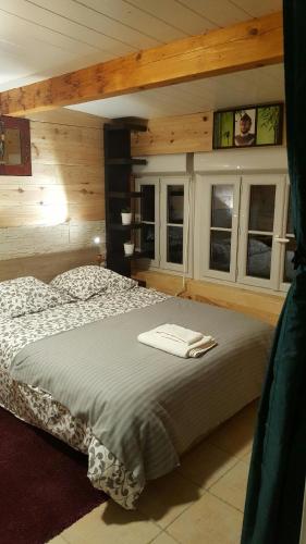 a large bed in a room with wooden walls and windows at La Palissandre in Tallard
