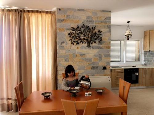 a woman sitting at a table in a kitchen at Grecia's Dhermi in Dhërmi