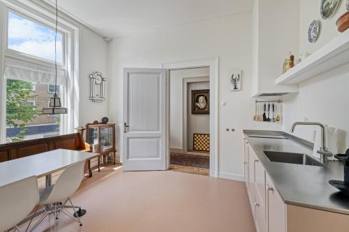a kitchen with white counters and a sink and a window at In de Pastorie Utrecht - Old rectory, just steps away from the city center in Utrecht
