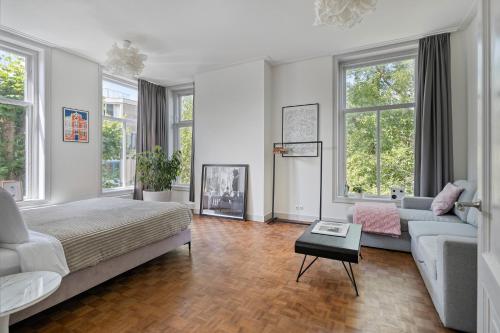 a large white bedroom with a bed and a couch at In de Pastorie Utrecht - Old rectory, just steps away from the city center in Utrecht