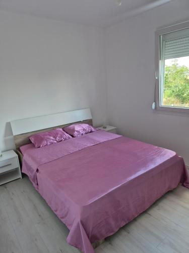 a bedroom with a bed with purple sheets and a window at Pećinska Vila in Kragujevac