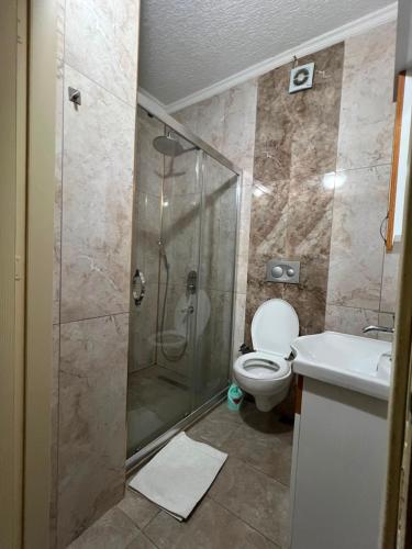 a bathroom with a shower and a toilet and a sink at Riwaner Hotel in Avcılar