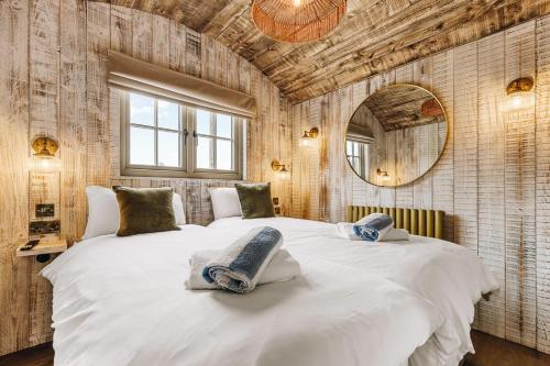 a bedroom with a large white bed and a mirror at Nestledstays – The Nest in Binsted