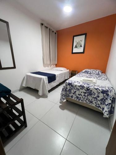 two beds in a room with orange walls at Aconchego do Caquende in Cachoeira