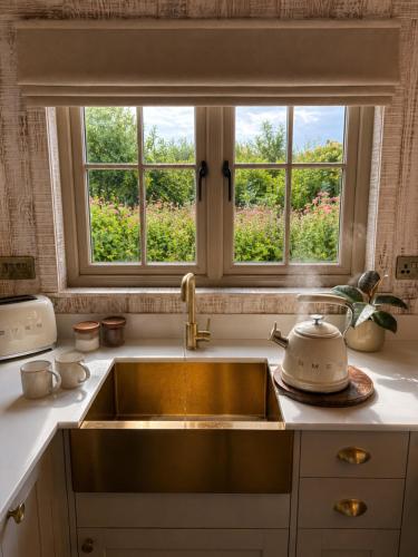 a kitchen with a sink and two windows at Nestledstays – The Meadow in Binsted