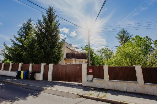 a fence in front of a house with the sun behind it at Marilyn Apartment in Nitra