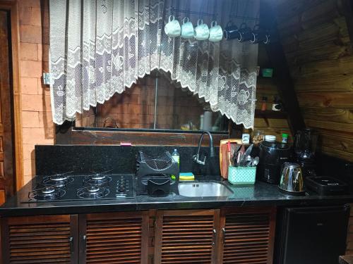 a kitchen with a stove and a sink and a window at Chalé in Jaraguá do Sul