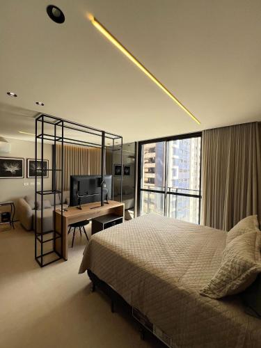 a bedroom with a bed and a desk and a television at Neo House in Maringá