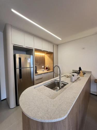 a kitchen with a sink and a refrigerator at Neo House in Maringá