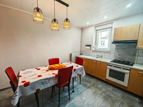 a kitchen with a table with red chairs and a kitchen with a stove at Appartement charmant et atypique, wifi, terrasse, jardin in Schleithal