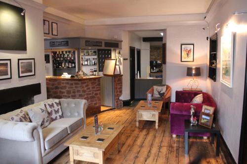 una sala de estar con sofás y mesas y un bar en The Lorna Doone Hotel en Porlock
