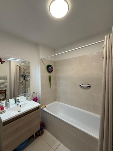 a bathroom with a white tub and a sink at Une petite chambre cosy in Dijon