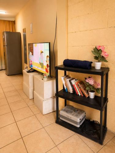 a room with a television and a shelf with books at Arianas Place 2 in Huehuetenango