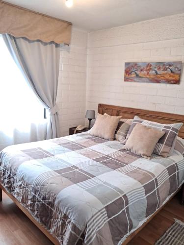 a large bed in a bedroom with a window at Apart Hotel Punto Real in Curicó