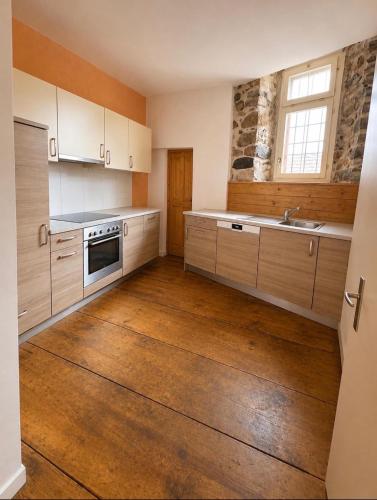 a kitchen with white cabinets and a wooden floor at Thun Arcades in Thun