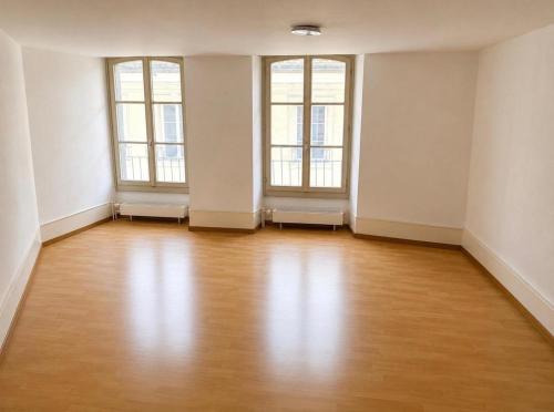 an empty room with two windows and a wooden floor at Thun Arcades in Thun