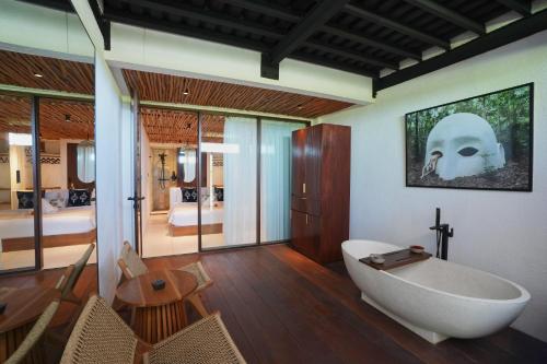 ein Badezimmer mit Badewanne und ein Schlafzimmer in der Unterkunft Casa Sol Hotel in Canggu