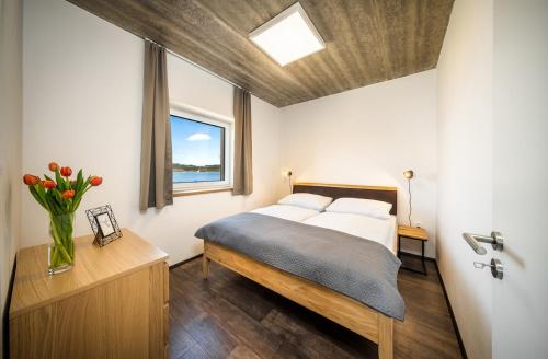 a bedroom with a bed and a vase of flowers on a table at Apartmány Panelka Costa Plana Lipno in Černá v Pošumaví