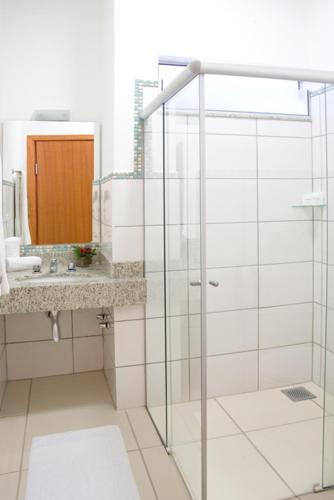 a bathroom with a glass shower and a sink at Ville Hotel Gramadão in Votuporanga