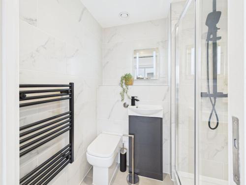 a white bathroom with a toilet and a shower at Luxury Two Bed | Sleeps 6 | 5 beds in Brent Station