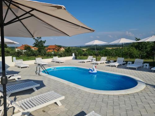 a swimming pool with chairs and an umbrella at Pećinska Vila in Kragujevac