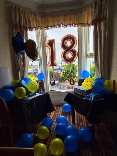 a room with blue and green balloons and a large window at St. Hilary Guest House in Llandudno