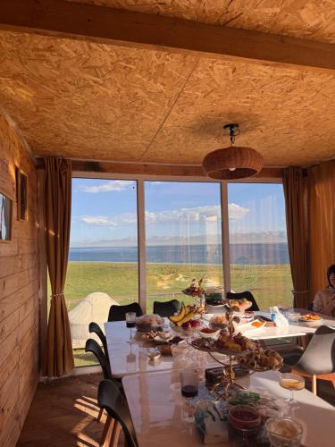 a dining room with a table and a large window at Yurt Camp by Fly Service in Song-Kul