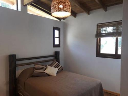 1 dormitorio con cama y lámpara de araña en Cabañas "Lola Mora" en Tandil