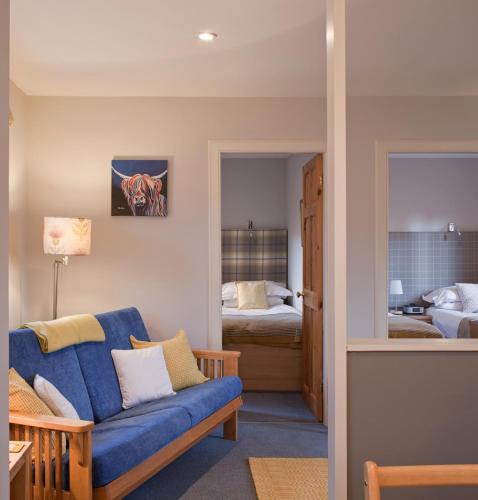 a living room with a blue couch and a bedroom at Shegarton Farm Cottages in Luss