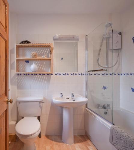 a bathroom with a toilet and a sink and a tub at Shegarton Farm Cottages in Luss