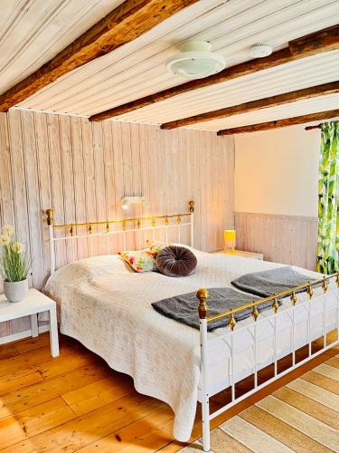 a bedroom with a white bed with a wooden ceiling at Rosengården - Viby B&Bi in Vretstorp