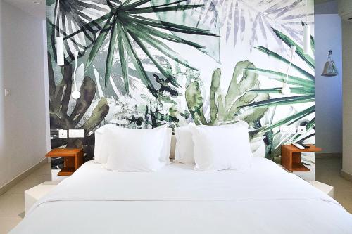 a bedroom with a white bed with a palm tree mural at Ganalé Hôtel in Dakar