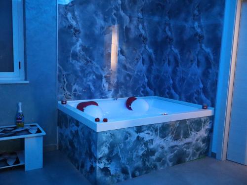a bathroom with a bath tub with a blue wall at Esmeralda B&B in Casa San Biagio