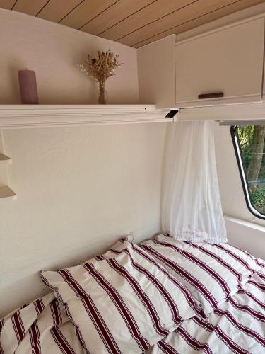 a bed in a small room with a window at La caravane dans le verger in Saint-Erblon