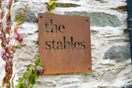 a sign on a stone wall that reads the stables at The Stables in Bearney
