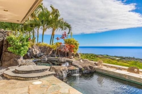 a home with a swimming pool and a rock wall at Waterfall House - Hawaii in Kailua-Kona