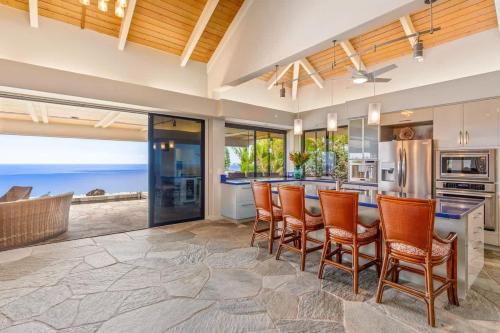a kitchen with a bar with chairs and the ocean at Waterfall House - Hawaii in Kailua-Kona