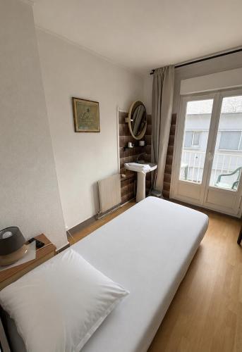 a large white bed in a room with a window at Hôtel de la poste in Saint-Valery-en-Caux