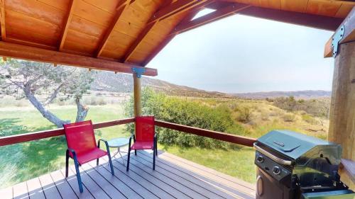 a porch with two red chairs and a grill at Pack Creek ~ Trails End in Spanish Valley
