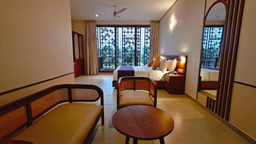 a hotel room with two beds and a table and chairs at Bliss Giriya By Bergamont in Tiruvannāmalai