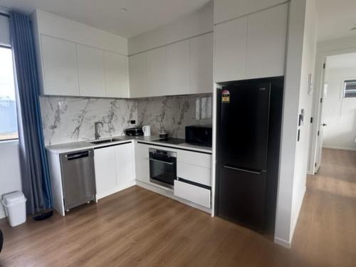a kitchen with white cabinets and a black refrigerator at 1 Bedroom Granny Flat D in Runciman