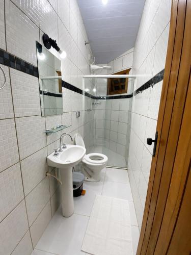 a white bathroom with a toilet and a sink at Pousada Recanto da Serrinha in Corumbá de Goiás
