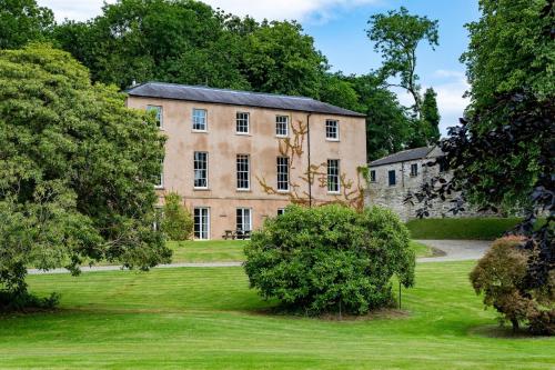 an old house in a field with trees at Glebe House in Sion Mills